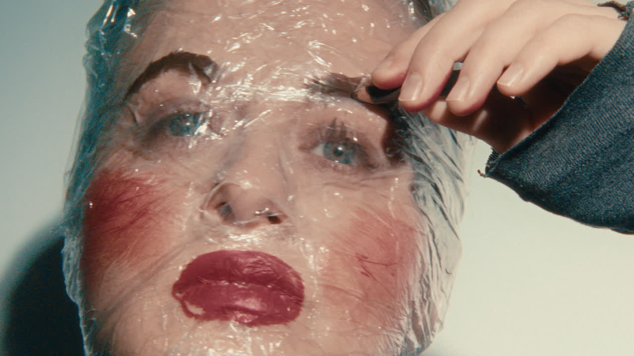 Woman with plastic wrap on face applying makeup