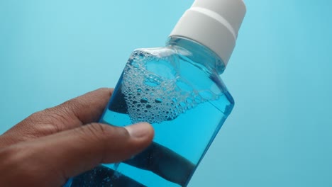 close up of a blue mouthwash bottle in a hand