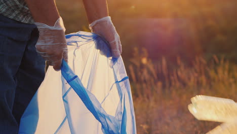 volunteers put trash in plastic bags cleaning the park and caring for the environment close-up shot