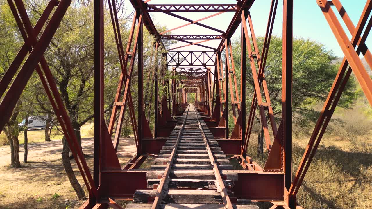 POV Moving Along Old Rusty Railway Bridge Tracks Through Nature