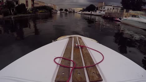 front of a small boat riding on water canals of empuriabrava on sunset