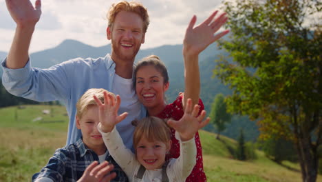 vrolijke familie poseert voor de camera op groene bergen. ouders hebben plezier met kinderen.