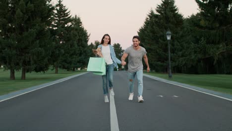una joven pareja de manos caminando por el parque de la ciudad. una familia joven divirtiéndose.