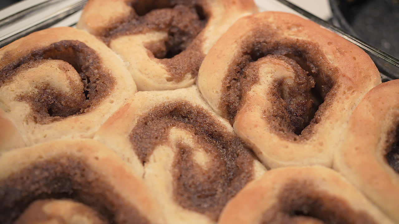 Golden brown cinnamon rolls fresh from the oven - isolated close up overhead motion