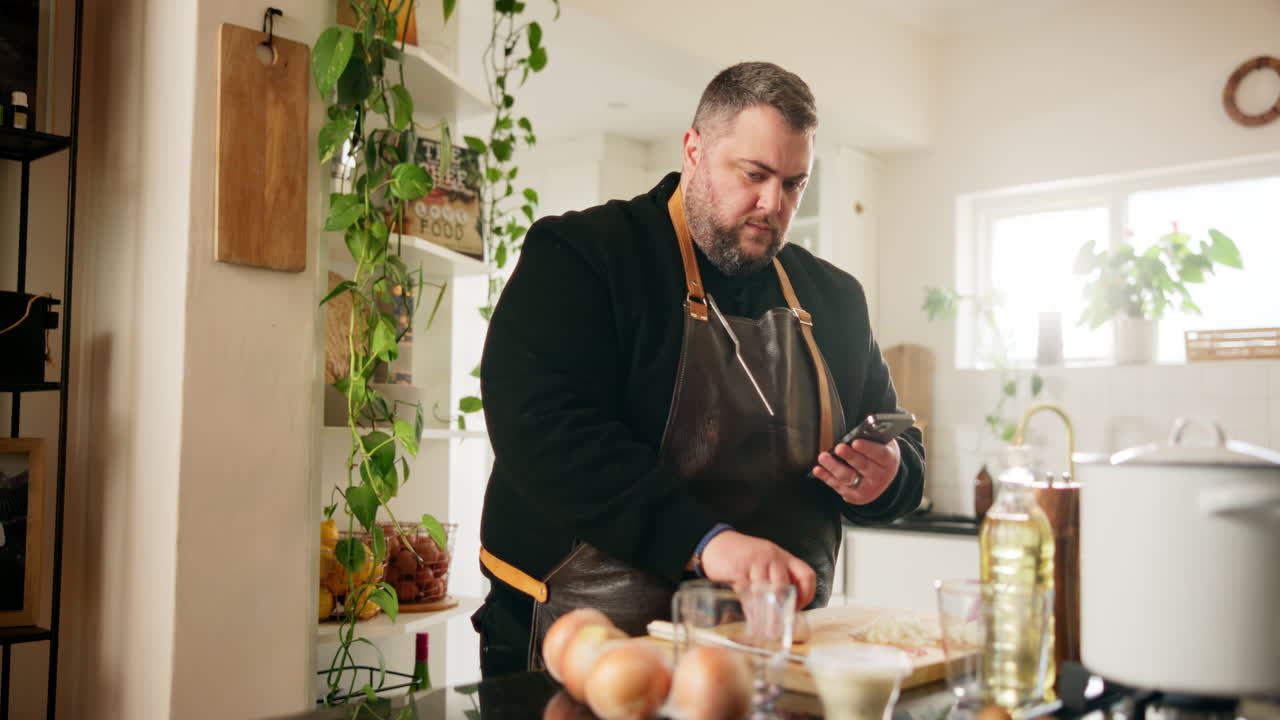 hombre cocinando en la cocina usando el teléfono para la receta