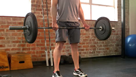 fit man lifting heavy barbell