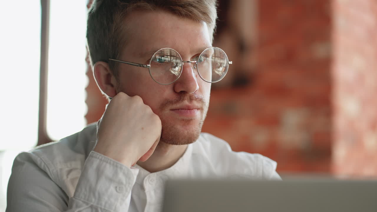 anxious and pensive man is reading news in laptop sitting in cafe closeup portrait of attractive guy with glasses