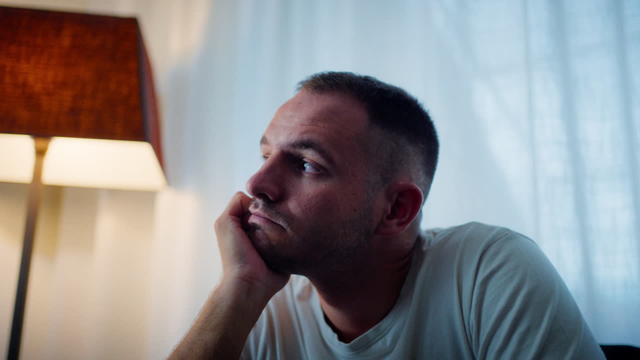 Man in thought resting his chin on hand, feeling bored and pensive