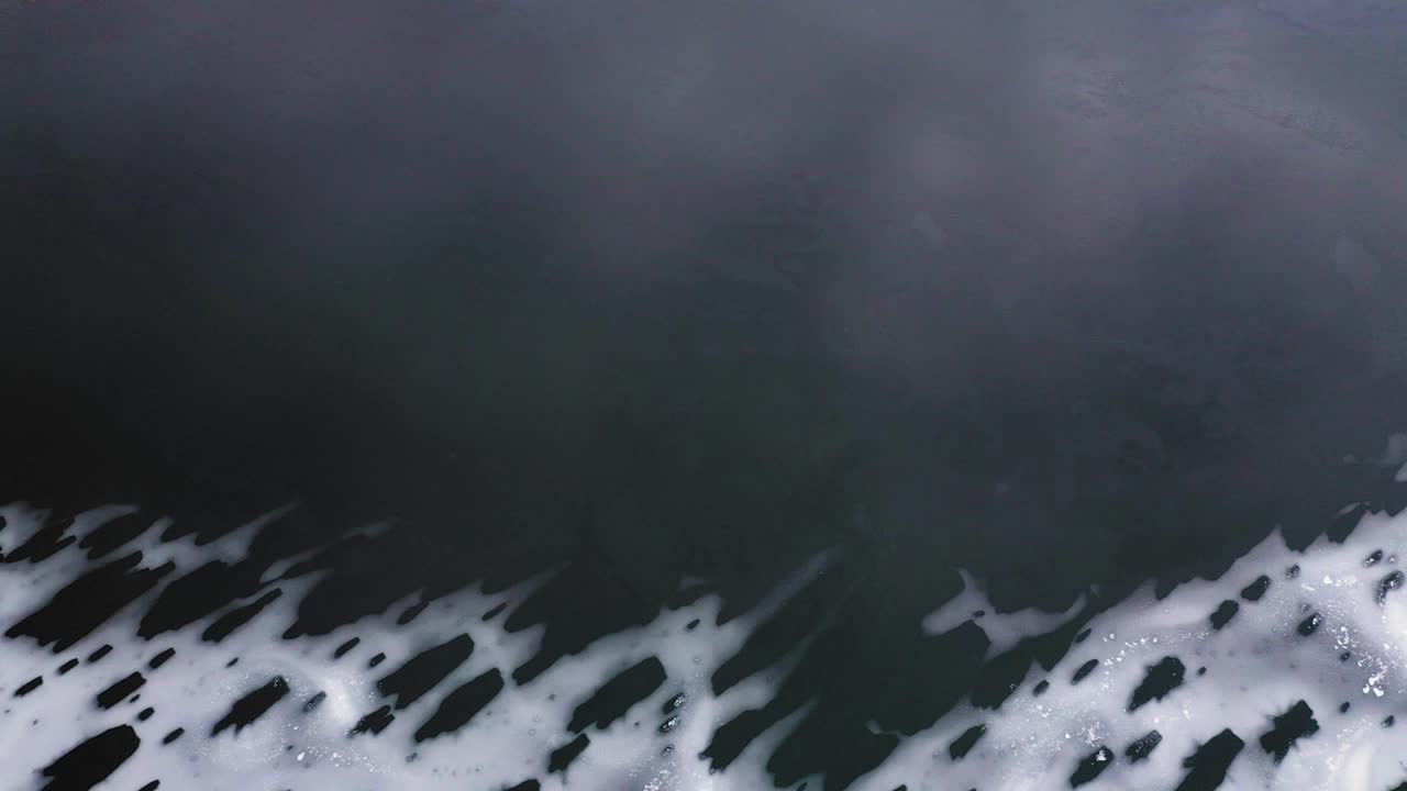 초겨울에 열린 물 옆에 있는 뾰족한 얼음 위의 하향식 공중 슬라이드