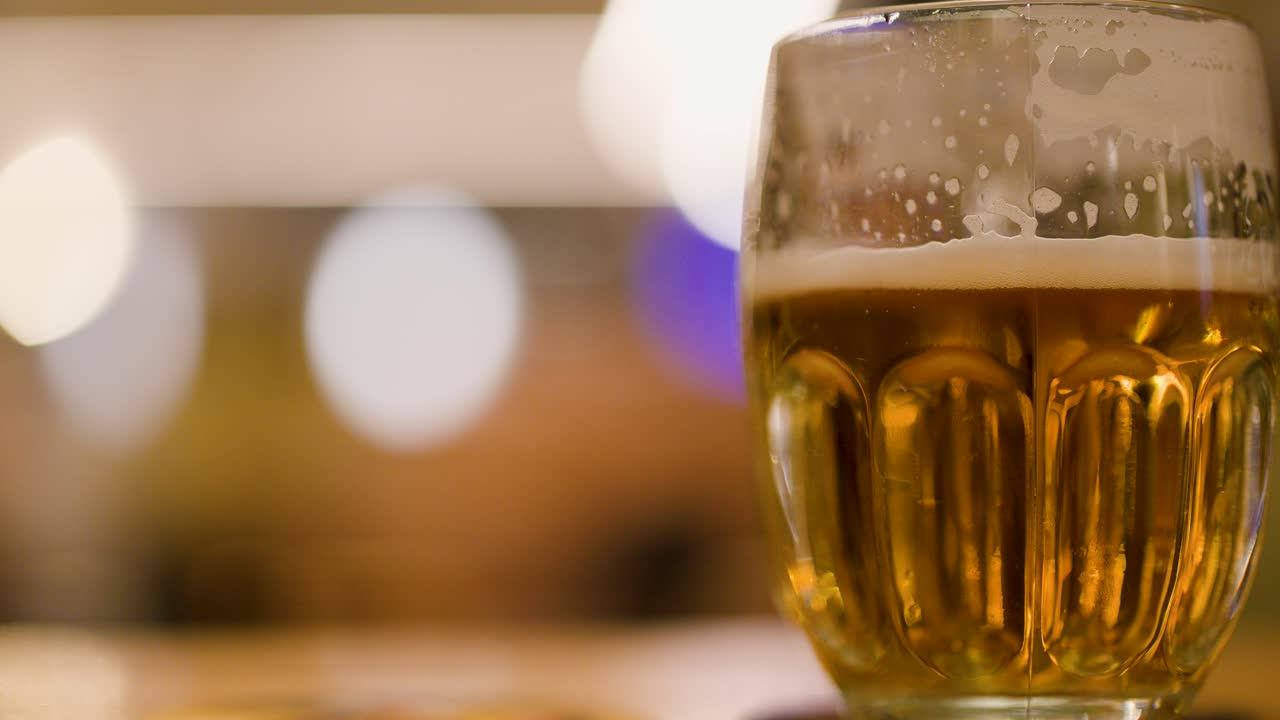 Closeup of foamy lager beer in glass mug at a cozy brewpub or brewery setting