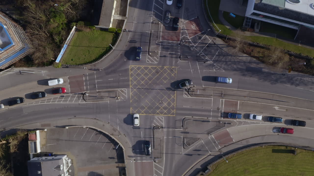 Timelapse of a busy intersection from a high aerial top-down view, capturing smooth traffic flow on a sunny morning