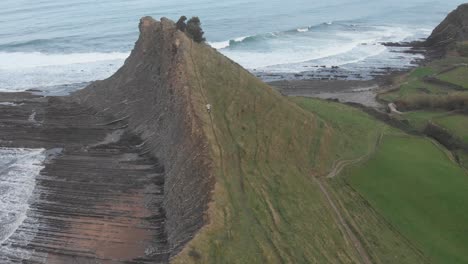 aerial drone shot of a man running to the top of a huge cliff