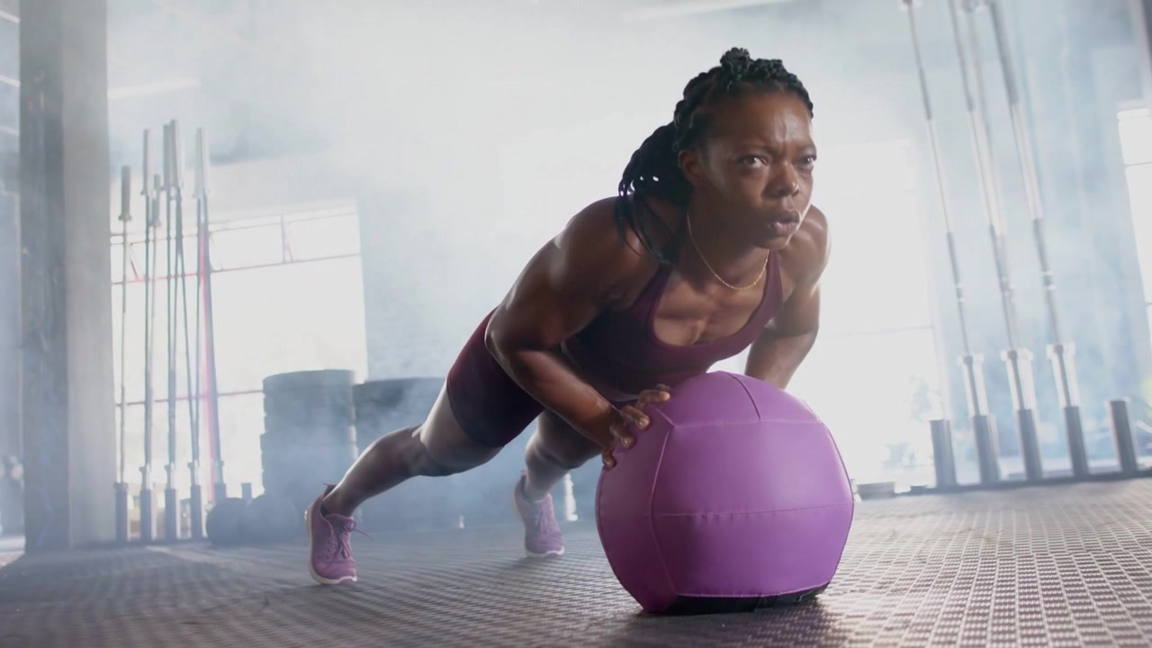 Fitness pro doing core pushups from plank on purple ball, motion lines showing core for stability