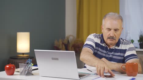 Home-office-worker-old-man-gets-frustrated-while-looking-at-phone.