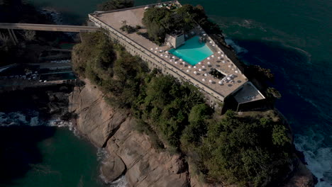 aerial view of rooftop swimming pool with beach umbrellas revealing the island the construction is build on and the wider coastal seascape of rio de janeiro