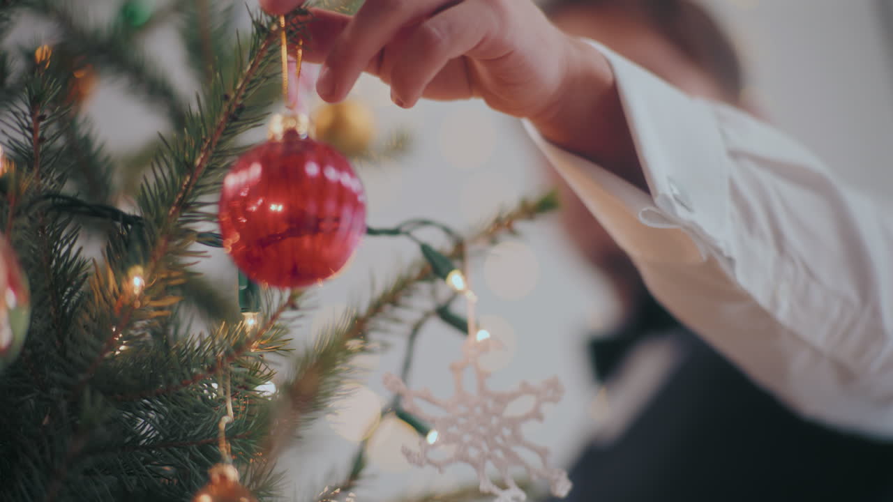 hombre colgando una joya roja en el árbol de navidad en casa
