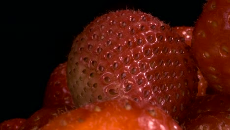 rotate of red strawberries on black background. close-up, camera rotation 360 degrees.