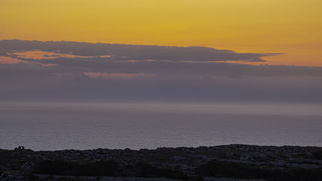 Timelapse-shot-of-white-clouds-rolling-over-sea-water-from-rocky-coastline-during-evening-time