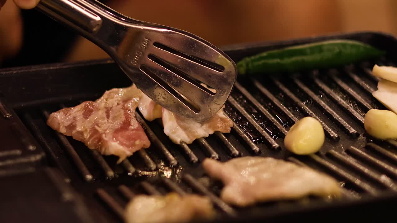 Cooking food on a grill with tongs
