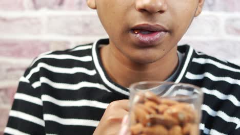 niño comiendo nueces de almendra de cerca ,