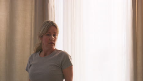 woman opening curtains to let the light in