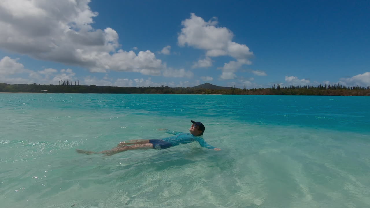청록색 열대 바다에서 편안하게 떠있는 여자