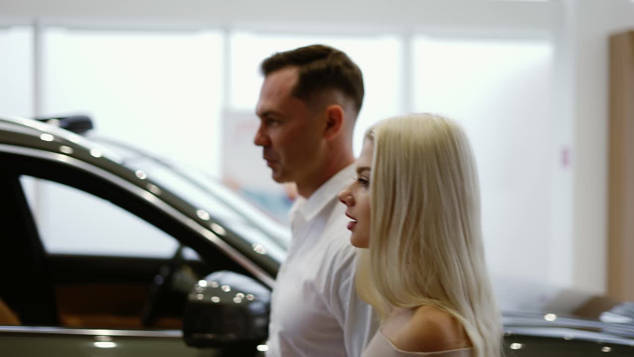 Un uomo con una bella donna bionda è venuto a scegliere un'auto in concessionaria.