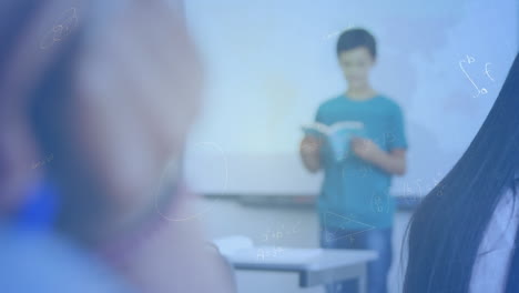 mathematical equations floating against caucasian boy reading a book in class at elementary school