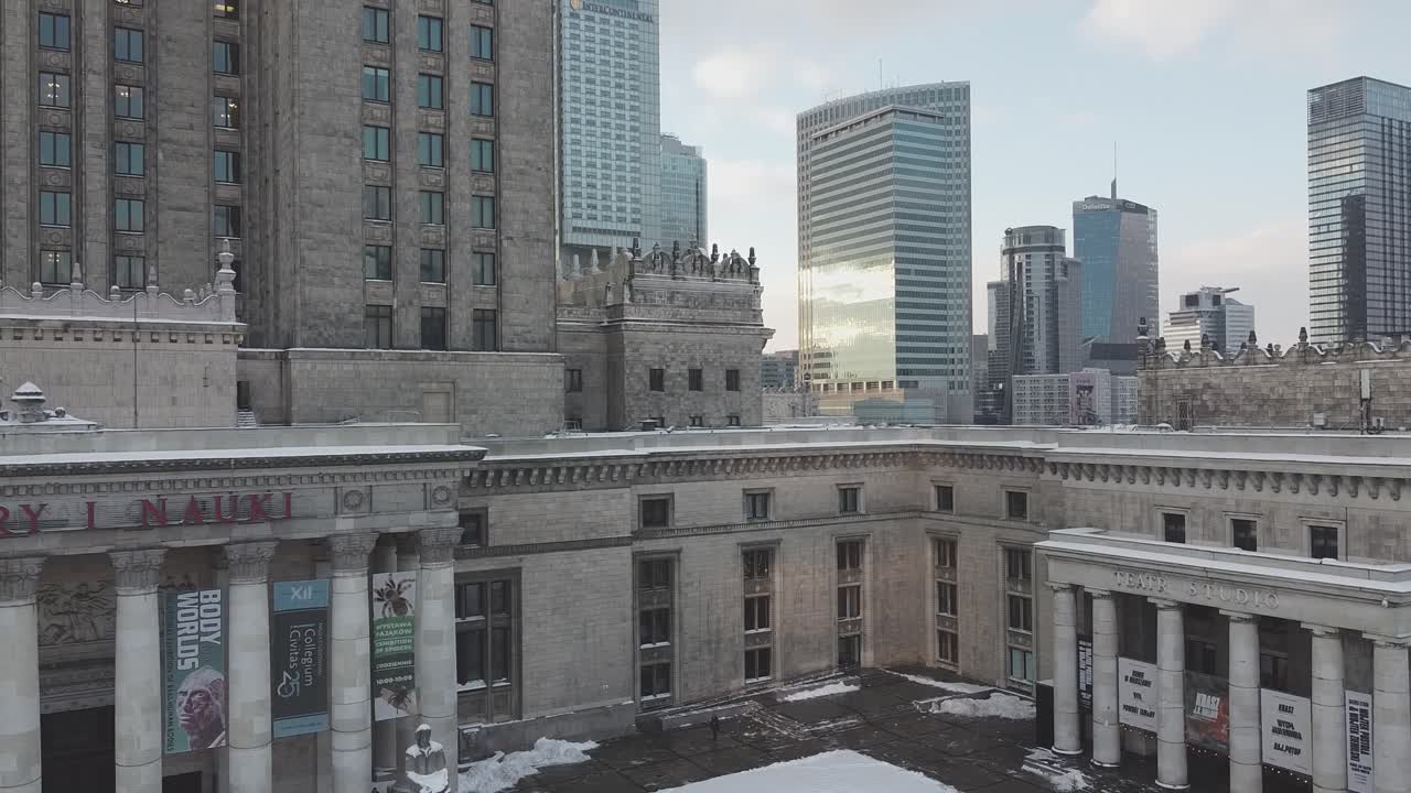Drone footage of Palace of culture and science building with sun rays and skyscrapers next to it
