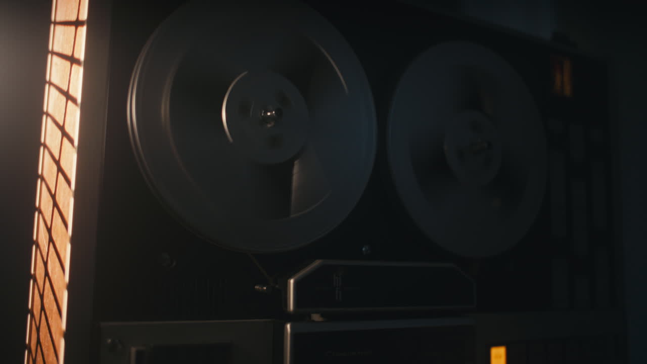 A vintage tape recorder spinning spools in a red blinking light