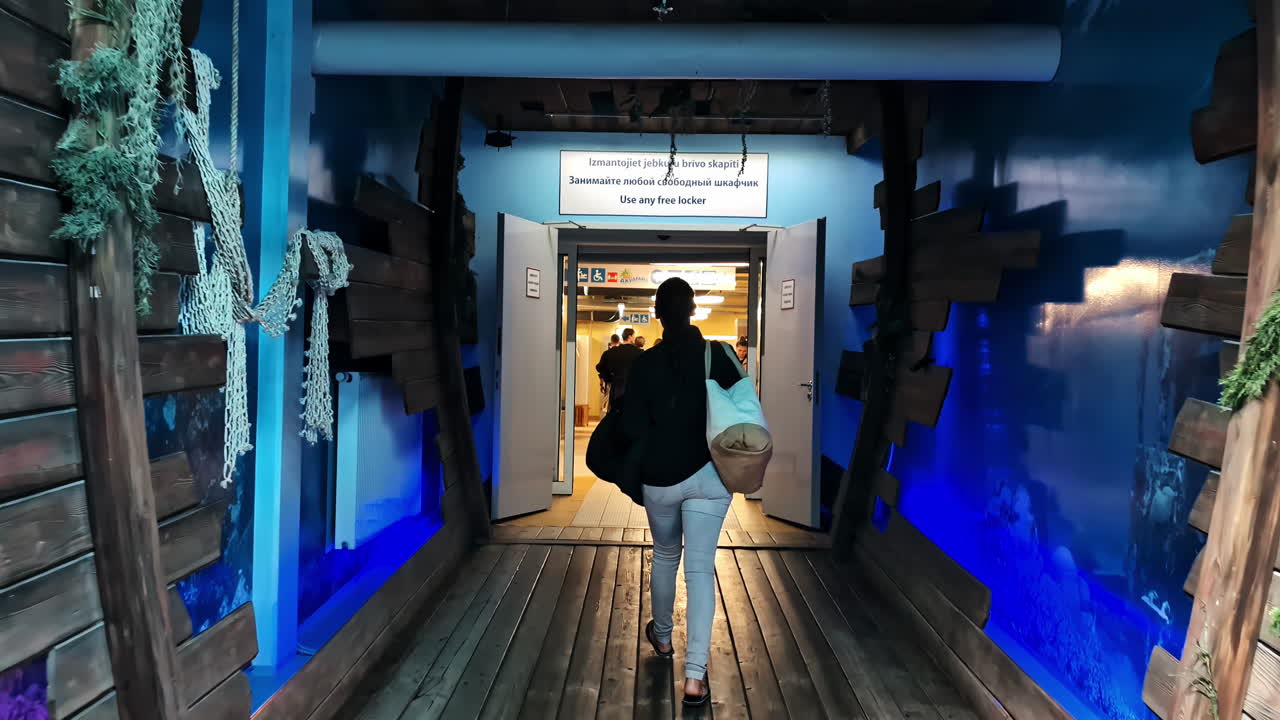 Woman walks through a tunnel-themed corridor toward shops at Viestura iela 24. Jūrmala, Latvia