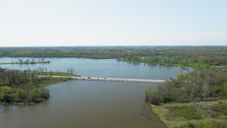 Aerial-steady-forward-moving-motion-over-a-canal-flowing-into-a-small-lake-in-a-public-park