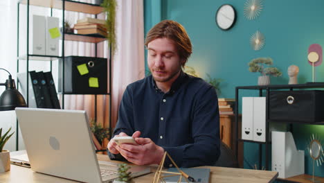 smiling business man using smartphone app online pointing showing like thumbs up remote distance job