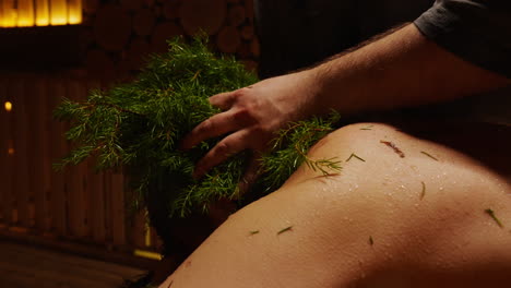 man receiving juniper treatment in a sauna