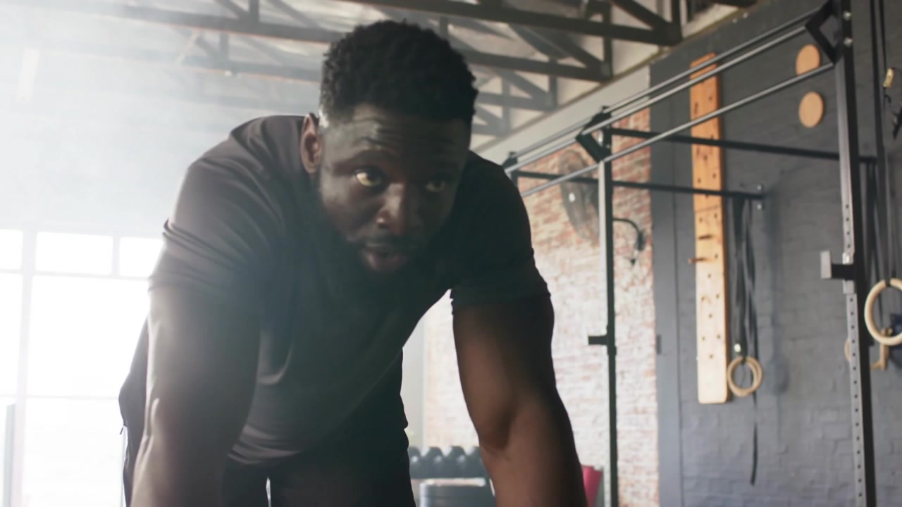 male athlete leaning after set, lifting head refocusing, preparing next set while gym bars sliding