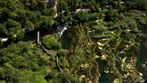 cascada roski - puente en roski slap con exuberantes plantas verdes y algas en un día soleado en croacia