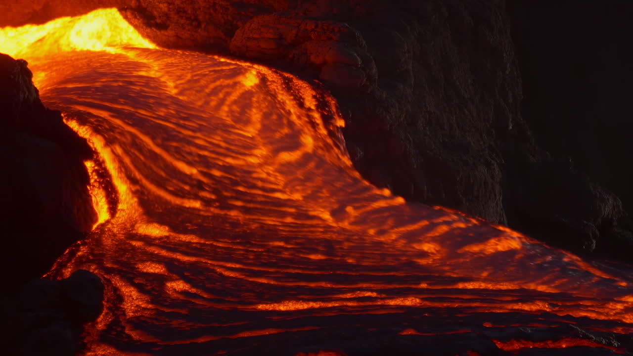 Fiume di lava fusa che scorre lungo un pendio vulcanico.