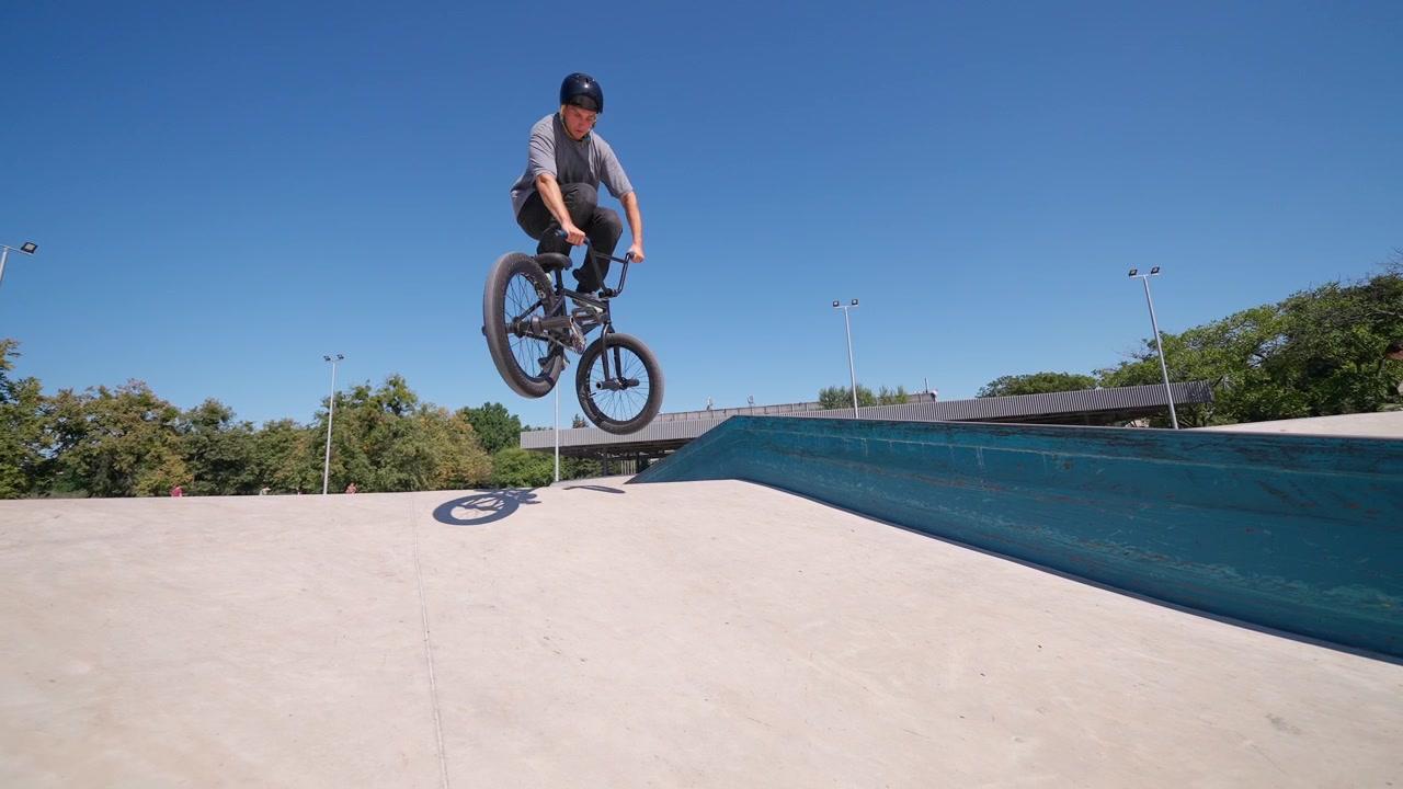 Giovane uomo che esegue un salto in BMX allo skatepark in una giornata di sole