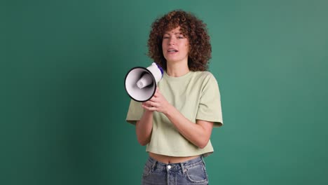 excited young woman screaming on loudspeaker in green studio