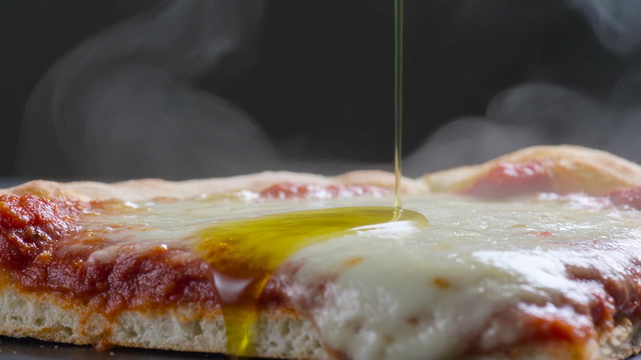 Versando un filo d'olio dorato su una fetta di pizza calda con mozzarella in studio, aggiungendo sapore e gocciolando.