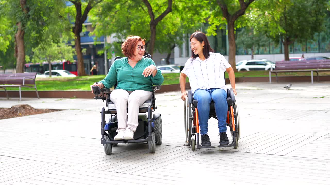 Two women in wheelchairs having a conversation in a park
