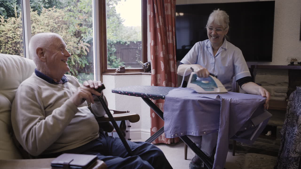 Caregiver Ironing for Elderly Man at Home