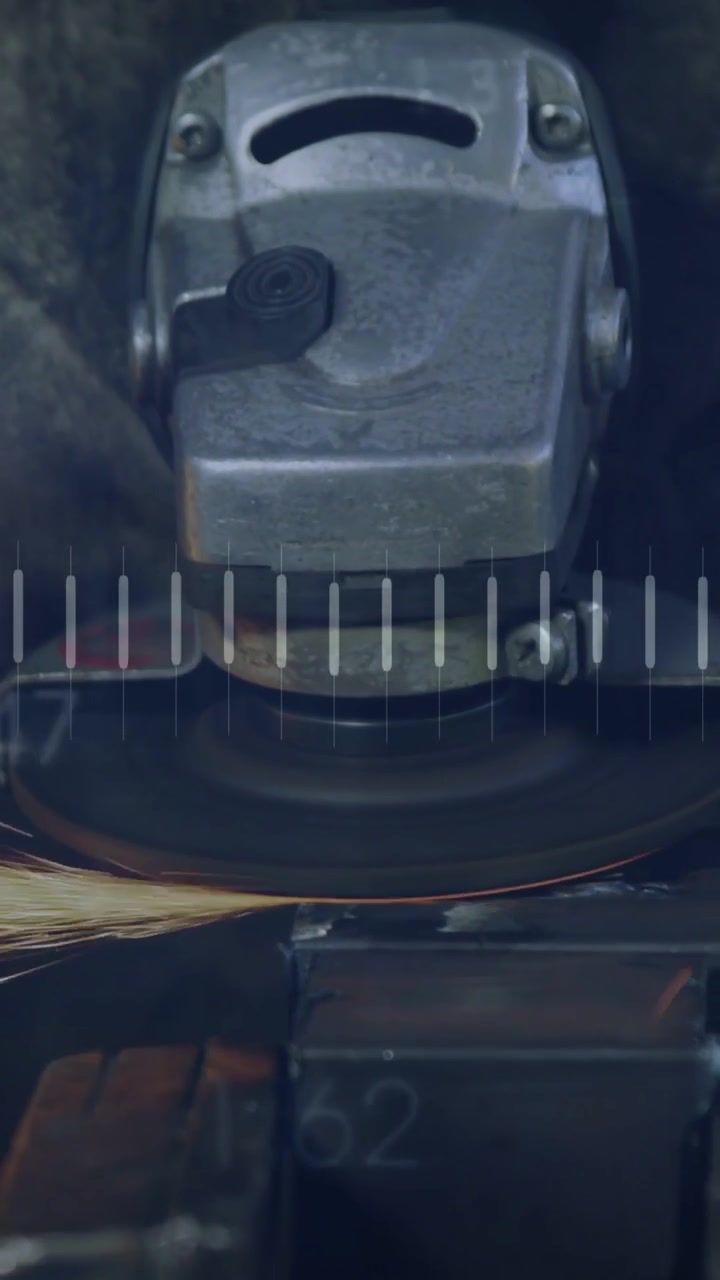 Video verticale: Operaio che usa una smerigliatrice per levigare metallo, producendo scintille, mentre barre a forma d'onda mostrano metriche.