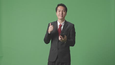 엄지손가락과 스마트폰을 들고 있는 사업가