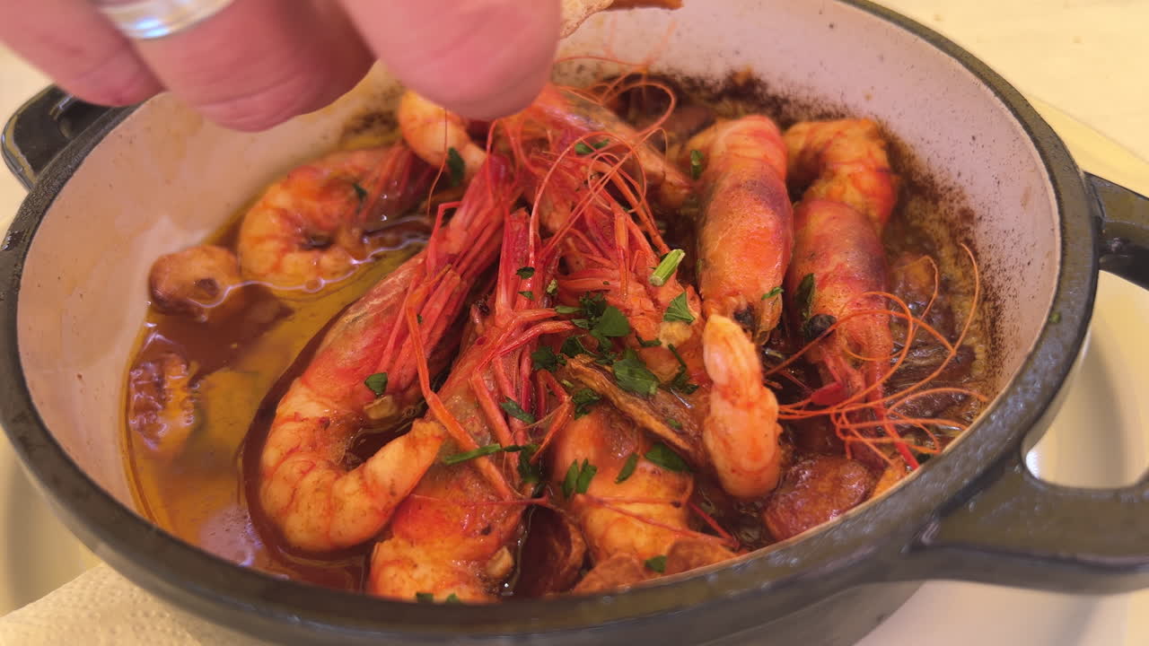Dipping bread in traditional Spanish Gambas pil pil on a hot plate in Marbella Spain, delicious spicy shrimp dish with garlic, eating sizzling food, 4K shot