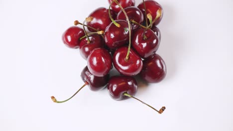 fresca y jugosa cereza roja girando lentamente sobre un fondo blanco. vista superior