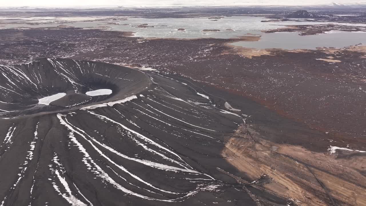 Flygvy över Hverfjalls vulkankrater nära sjön Mývatn, Island. Snöklädda sluttningar och frusna lavafält kontrasterar mot de stilla sjöarna och den karga isländska terrängen