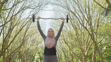 woman in hijab lifting barbell in park