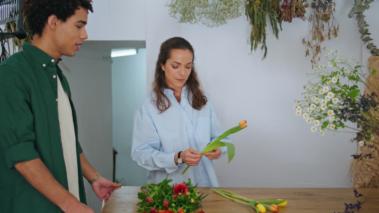 아프리카 고객은 꽃 가게에서 꽃을 구입합니다. 꽃가게 소녀는 봄 꽃받침을 일합니다.