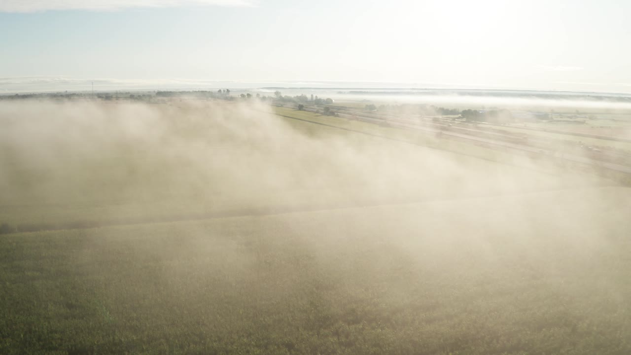 밝은 녹색 농장 필드와 평원을 통과하는 고속도로 위에 매달려 있는 아침 안개 위의 옅은 푸른 하늘
